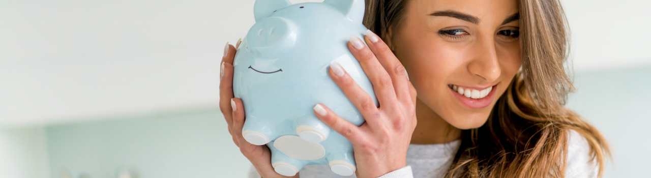 woman smiling and holding a piggy bank